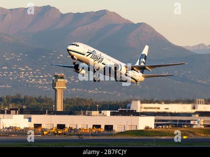 Boeing 737 der Alaska Airlines verlässt den Flughafen Anchorage vor dem Berg- und Flugsicherungsturm. Flugzeug registriert als N305AS. Stockfoto