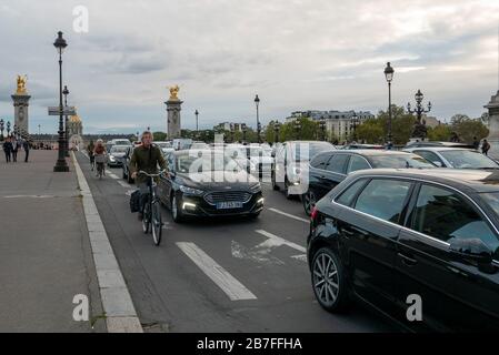 Radfahrer fahren in der Hauptverkehrszeit auf der Pont Alexandre III in Paris, Frankreich, Europa an langsam fahrenden Autos in einem Stau vorbei Stockfoto