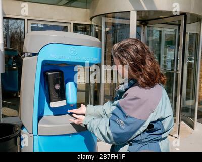 Oak Park, Illinois, USA. März 2020. Eine Frau benutzt die tragbare Handwaschstation am Haupteingang der Village Hall, bevor sie ihre frühe Stimme in diesem westlichen Vorort von Chicago abnimmt. Stockfoto