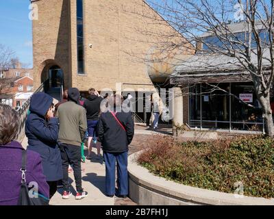 Oak Park, Illinois, USA. März 2020. Die frühen Wähler für die Wahl der Illinois Primary am Dienstag wurden getroffen, um sich heute außerhalb der Village Hall zusammenzuschließen, um zu vermeiden, dass sie im Gebäude zusammengedrängt werden. Auch Schulen und Bibliotheken sind bis zum 31. März geschlossen, um Coronavirus/COVID-19 von der Verbreitung fernzuhalten. Stockfoto