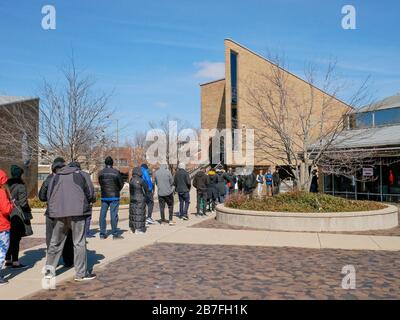 Oak Park, Illinois, USA. März 2020. Die frühen Wähler für die Wahl der Illinois Primary am Dienstag wurden getroffen, um sich heute außerhalb der Village Hall zusammenzuschließen, um zu vermeiden, dass sie im Gebäude zusammengedrängt werden. Auch Schulen und Bibliotheken sind bis zum 31. März geschlossen, um Coronavirus/COVID-19 von der Verbreitung fernzuhalten. Stockfoto