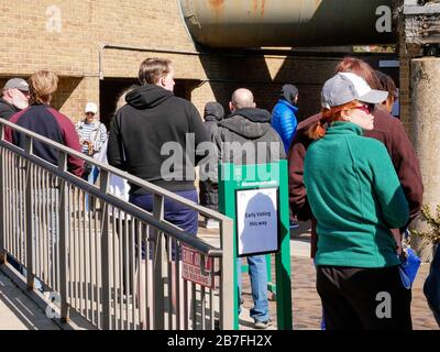 Oak Park, Illinois, USA. März 2020. Die frühen Wähler für die Wahl der Illinois Primary am Dienstag wurden getroffen, um sich heute außerhalb der Village Hall zusammenzuschließen, um zu vermeiden, dass sie im Gebäude zusammengedrängt werden. Auch Schulen und Bibliotheken sind bis zum 31. März geschlossen, um Coronavirus/COVID-19 von der Verbreitung fernzuhalten. Stockfoto