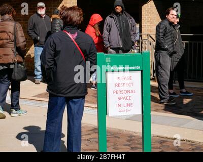 Oak Park, Illinois, USA. März 2020. Die frühen Wähler für die Wahl der Illinois Primary am Dienstag wurden getroffen, um sich heute außerhalb der Village Hall zusammenzuschließen, um zu vermeiden, dass sie im Gebäude zusammengedrängt werden. Auch Schulen und Bibliotheken sind bis zum 31. März geschlossen, um Coronavirus/COVID-19 von der Verbreitung fernzuhalten. Stockfoto