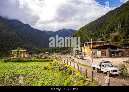 Ein Pickup-Truck am Ende der Feldstraße in der Nähe eines Wegfahrers im kleinen Dorf Shana, Bhutan Stockfoto