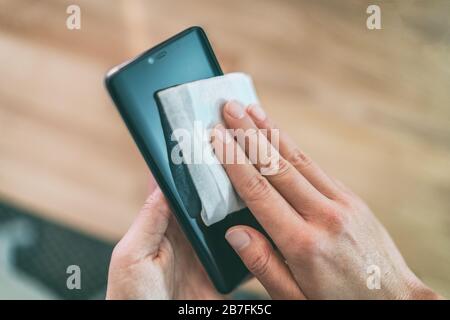 Reinigung des Handy-Bildschirms mit desinfizierenden feuchten Wischtüchern für eine saubere, präventive Reinigung des Smartphones für die Vorbeugung von COVID-19 Coronavirus gegen Ausbrüche. Stockfoto