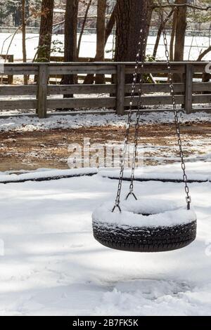 Ein nach einem Winter-Schneesturm in einem öffentlichen Park schneebedeckter Reifenschwung. Stockfoto