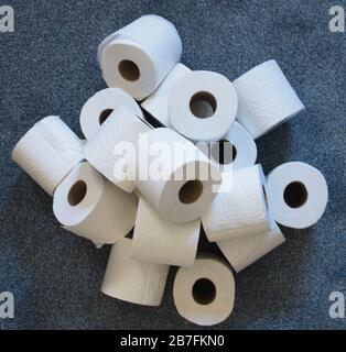 Stapel von toilettenpapierrollen auf einem blauen Home-Teppich von oben. Stockfoto