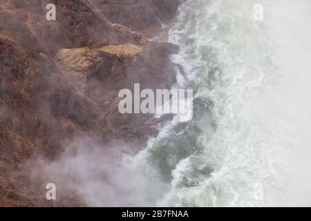 Wenn Sie auf die Basis der Lower Falls im Yellowstone River hinunterblicken, interagieren Wellen und Nebel mit den Felswänden des Canyons im Yellowstone National Stockfoto