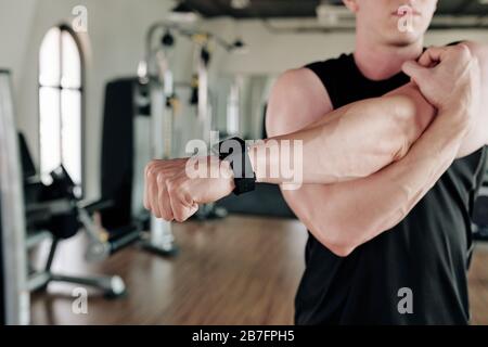Sportler, die beim Aufwärmen im Fitnessstudio eine elegante Uhr tragen Stockfoto