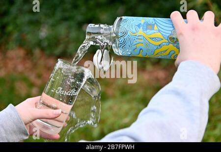 11. März 2020, Schleswig-Holstein, Westerland/Sylt: ILLUSTRATION - Leitungswasser aus einer "Flasche", die im Touristeninformationsbüro erhältlich ist, wird in ein Glas mit der Aufschrift "Inselliebe" gefüllt. Sylt wird am 22. März offiziell zu einem von 12 Wasserbezirken im ganzen Land des Vereins "ein Tipp: Hahn", der sich für den gestiegenen Verbrauch von Leitungswasser einsetzt. (Zu dpa "Wasserumkehr auf der Insel - Sylt will Leitungswasserverbrauch fördern") Foto: Carsten Rehder / dpa Stockfoto