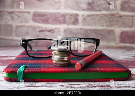 Nahaufnahme von Münzen, Notizblock und Bleistiften auf dem Tisch Stockfoto