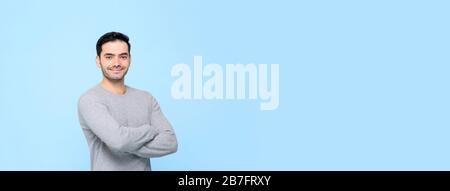 Porträt eines lächelnden freundlichen gutaussehenden Mannes in einfarbiigem grauem T-Shirt mit in hellblauem Bannerbakerboden isolierten Armen mit Kopierraum Stockfoto