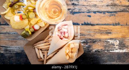 Tapas, Pinchos und Weinpanorama mit Kopierbereich. Käse, Jamon, würzige gildas und Kartoffelchips auf einem Holztisch in einem Café im Freien Stockfoto