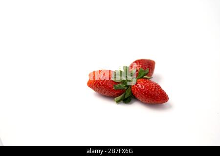 Drei reife frische rote Erdbeeren mit grünen Blättern isoliert auf weißem Grund. Stockfoto