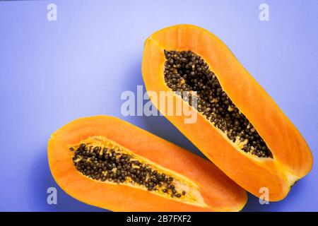 Reife Papayafrucht halbiert isoliert auf blauem Grund. Draufsicht auf frische Papaya-Fruchthälften mit Samen. Vegane Ernährung, exotische Früchte Konzept. Horizo Stockfoto