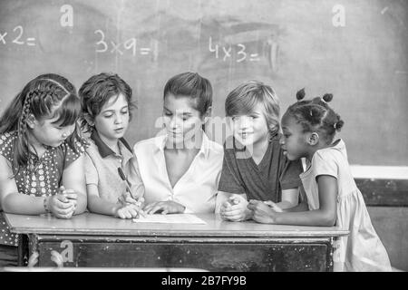 Weibliche Lehrerin erklärt Mathematik dem primären multiethnischen Klassenzimmer. Stockfoto
