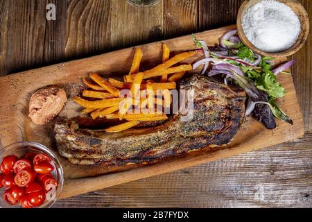Draufsicht auf gegrillte, saftige Schweinebrippen mit Pommes Auf einem Holzbrett Stockfoto