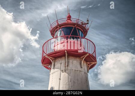Historischer roter Leuchtturm auf dem Hintergrund des blauen dramatischen Himmels. Stockfoto