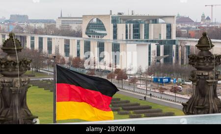 Blick auf die Residenz des Bundeskanzlers mit schwenkender deutscher Flagge im Vordergrund. Stockfoto