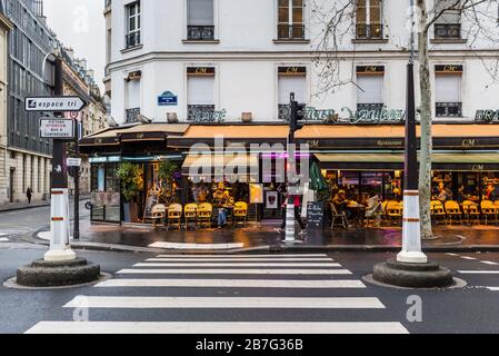 Paris, Frankreich - 23. Dezember 2018: Typischer Blick auf die gemütliche Straße mit Tischen der Café-Terrasse in Paris, Frankreich. Architektur und Wahrzeichen von Paris. Stockfoto