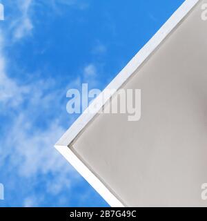 Abstrakter minimaler Architekturhintergrund mit weißer Betondecke unter blauem Himmel, quadratisches Foto Stockfoto