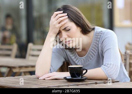 Depressive Mädchen beschweren sich allein mit der Hand auf dem Kopf auf einer Kaffee-Shop-Terrasse Stockfoto