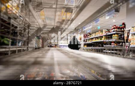 Berlin, Deutschland. März 2020. Ein Kunde läuft in einem Supermarkt im Berliner Stadtteil Friedenau an leeren Regalen vorbei. Hier sollen im Laufe des Tages neue Waren geliefert werden. Credit: Kay Nietfeld / dpa / Alamy Live News Stockfoto