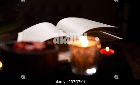 Wahrsagerraum mit offenem Vorhersagebuch auf dem Tisch mit Kerzen, Nahaufnahme Stockfoto