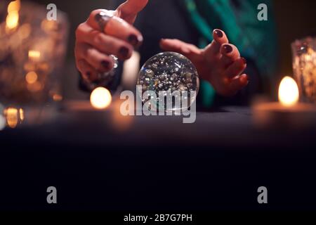 Hände von nicht erkennbaren Wahrsagern mit einem Ball von Vorhersagen im dunklen Raum Stockfoto