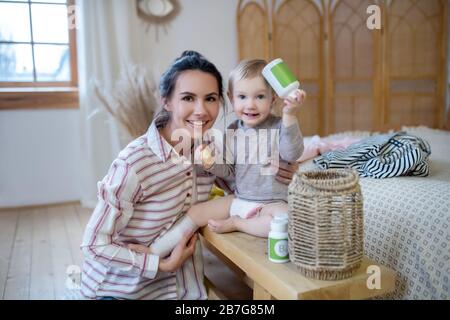 Mutter und Tochter sitzen zusammen, Mädchen halten Flasche mit Binde auf dem Bein Stockfoto