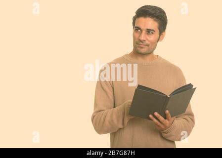 Jungen schönen persischen Mann mit Buch beim Denken Stockfoto