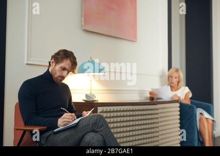 Porträt eines eleganten Mannes und einer Frau, die mit Geschäftsdokumenten im eleganten Interieur arbeiten, Kopienraum Stockfoto