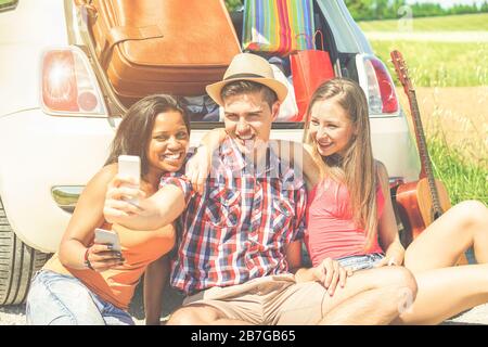 Fröhliche Freunde, die selfie Foto stehen neben dem Auto voller Koffer und Taschen - junge Leute, die sich in den Ferien auf der Straße lustig machen - Reisen und Freunde Stockfoto