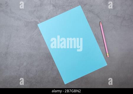 Flach, Ansicht von oben, blau Blatt und Bleistift auf einem grauen strukturierten Hintergrund Stockfoto