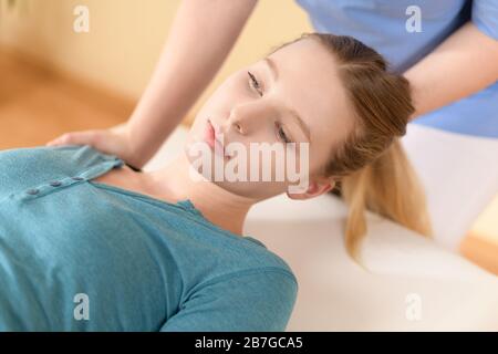 Physiotherapeutin oder Chiropraktikerin, die den Hals des Patienten verstellt. Physiotherapie, Rehabilitationskonzept. Zugeschnittene Aufnahme in der Draufsicht. Stockfoto