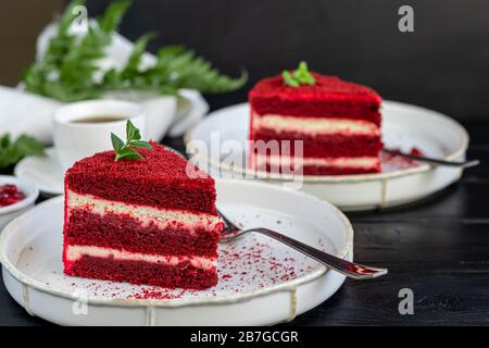 Kuchenroter samt auf zwei weißen Tellern, zwei Portionen. Auf schwarzem Hintergrund. Geburtstag, Feiertage, Süßigkeiten. Stockfoto