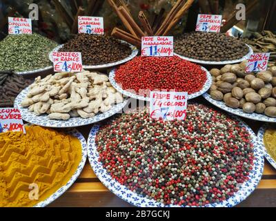 Bunte Keramikplatten mit verschiedenen frischen Gewürzen in einem Schaufenster. Bunte Paprika, grüne Pfefferkörner, Safran, Curry, Paprika, Ingwer und Chili Stockfoto