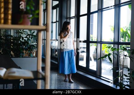 Asiatische Frau, die einen Anruf hat und nach draußen schaut Stockfoto