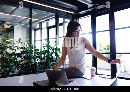 Arbeitende asiatische Frau, die auf ihrem Schreibtisch sitzt Stockfoto