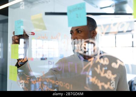 Afroamerikanischer Mann, der auf Haftnotizen schreibt Stockfoto