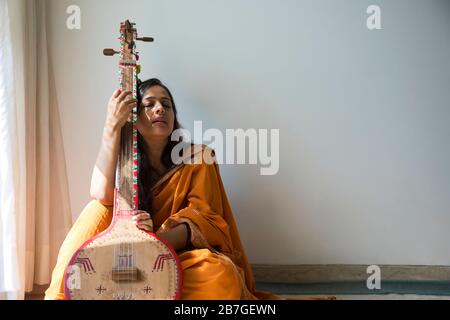 Frau in ihrem Element, die Musik auf ihrer Tambura spielt. Stockfoto