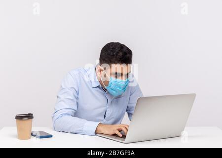 Grippekranke Büroangestellte in hygienischer Maske arbeiten auf Laptop, verwenden Schutzfilter gegen ansteckende Krankheit Coronavirus und sehen verrückt aus Stockfoto