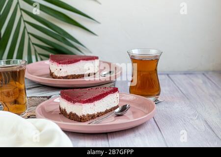 Käsekuchen auf zwei weißen Platten, zwei Portionen. Auf weißem Grund mit frischen Beeren dekoriert. Geburtstag, Feiertage, Süßigkeiten. Ich trinke in der Nähe. Stockfoto