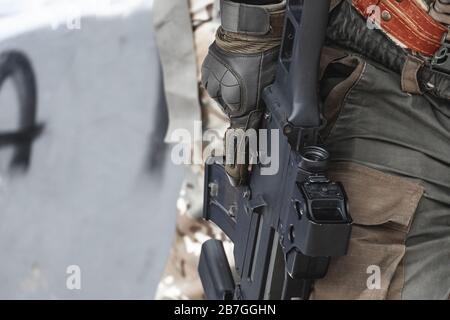 Der eingestellte Soldat hält ein gesenktes Gewehr in der Hand. Nahaufnahme. Stockfoto