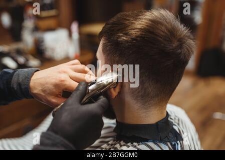 Barber hält Kamm und schneidet die Haare des Kunden Stockfoto