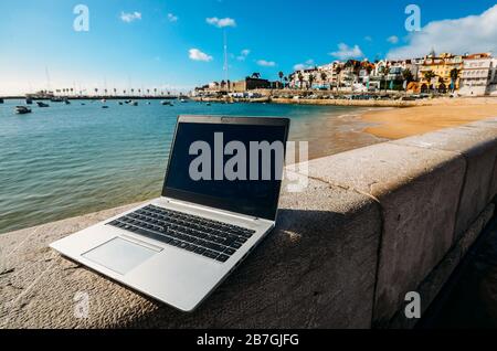 Generisches Notebook Laptop am sonnigen, einsamen sandigen Strand im Hintergrund. Paradise Home Office Konzept speziell bei Coronavirus Covid-19 Ausbruch Stockfoto