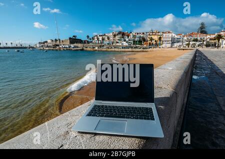 Generisches Notebook Laptop am sonnigen, einsamen sandigen Strand im Hintergrund. Paradise Home Office Konzept speziell bei Coronavirus Covid-19 Ausbruch Stockfoto