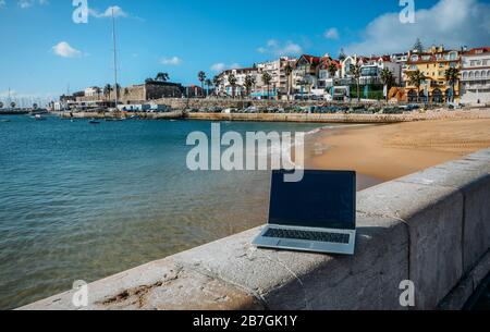 Generisches Notebook Laptop am sonnigen, einsamen sandigen Strand im Hintergrund. Paradise Home Office Konzept speziell bei Coronavirus Covid-19 Ausbruch Stockfoto