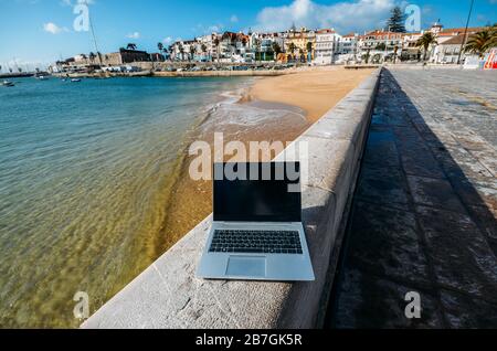 Generisches Notebook Laptop am sonnigen, einsamen sandigen Strand im Hintergrund. Paradise Home Office Konzept speziell bei Coronavirus Covid-19 Ausbruch Stockfoto