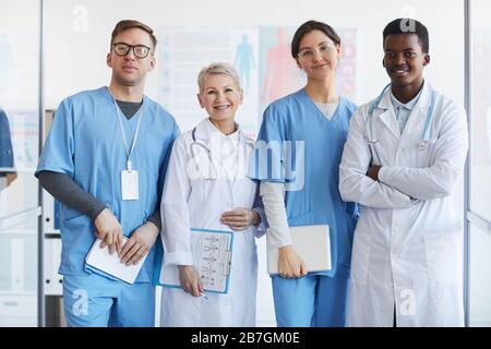 Taille oben Porträt der multiethnischen Gruppe von Ärzten, die die Kamera betrachten, während sie zusammen im Klinikinneren posieren Stockfoto